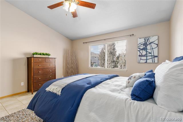 Bedroom with white bedding, blue blankets, and a wooden chest of drawers beside the window.