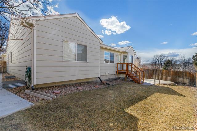 Single-story home's rear exterior with a small wooden deck and fenced winter yard.