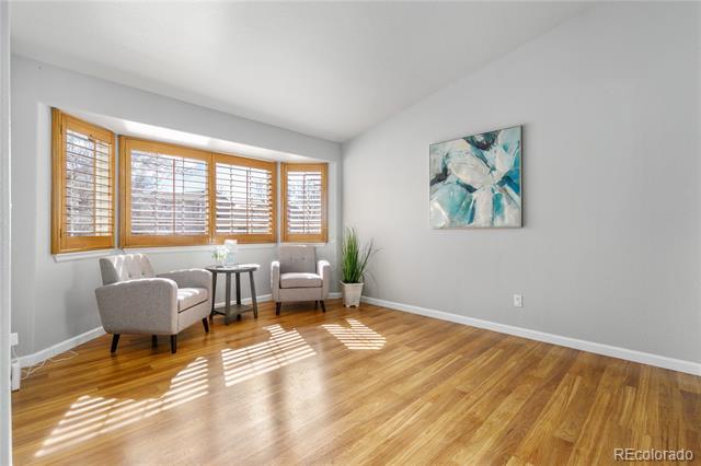 Sitting area with two armchairs, wood-framed windows, and sunlight across hardwood floors.