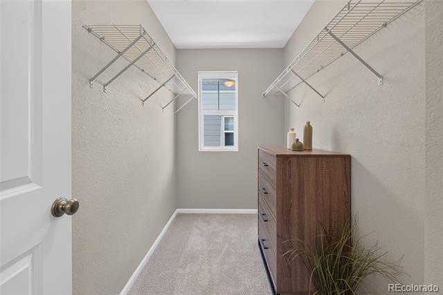 Walk-in closet with wire shelving, a far-end window, and a wooden chest of drawers.