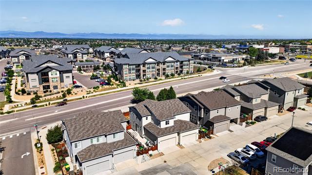 Aerial view of neighborhood homes beside a wide road, with distant mountains on the horizon.
