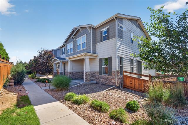 Two-story gray home with a stone foundation, landscaped rock garden, and concrete walkway.