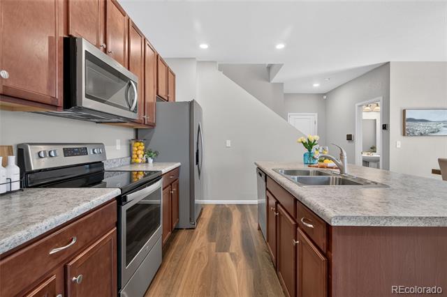 Kitchen with reddish wood cabinets, granite counters, stainless steel appliances, and a large island sink.
