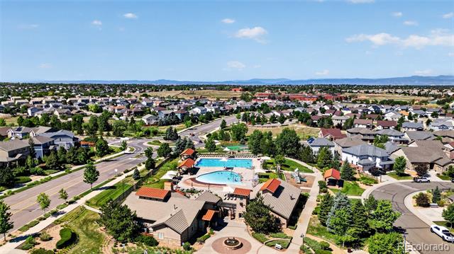 Aerial view of a neighborhood with a community pool and clubhouse, homes, and distant mountains.