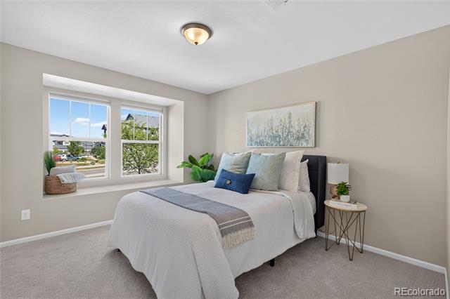Staged bedroom with a white bed, layered pillows, and a large window overlooking greenery.