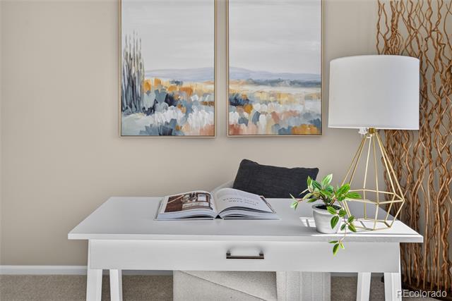 Home office with a white desk, open book, gold tripod lamp, and abstract artwork.