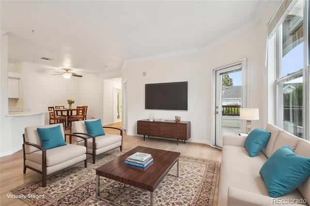 Virtually staged living room with teal cushions, a dark wood coffee table, and a dining area beyond.