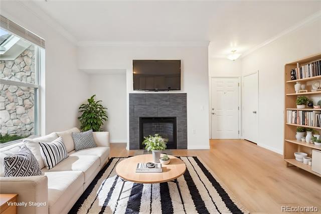 Virtually staged living room with a white sofa, striped rug, and fireplace beneath a wall-mounted television.