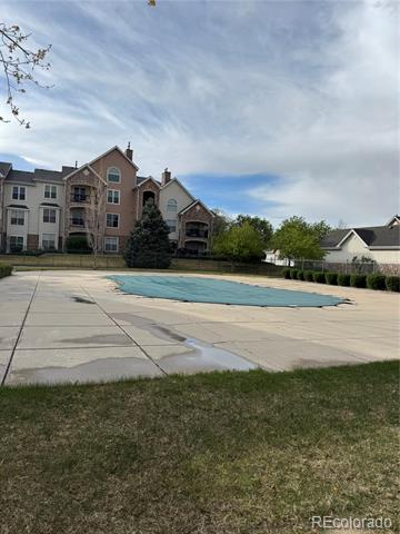 Condominium complex behind a swimming pool and paved deck.