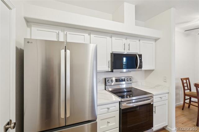 Kitchen with white cabinets, stainless steel appliances, and hardwood floors.