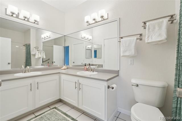 Bathroom with a white double vanity, two sinks, large mirrors, and tiled floor.
