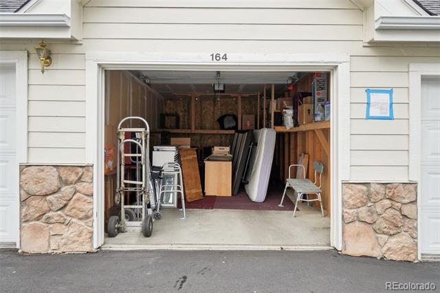 Open garage packed with stored items, including boxes, shelving, carts, and a ladder.