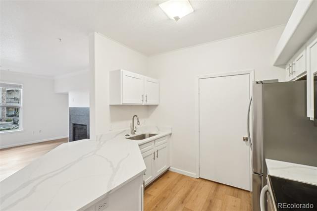 Bright kitchen with a large veined white island, stainless steel appliances, and light wood flooring.