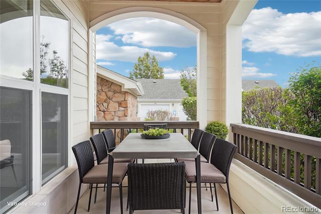 Covered patio with a dark outdoor dining set and arched opening overlooking neighboring homes and trees.