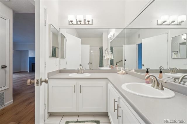 Bathroom with a long white double vanity, two sinks, and broad wall mirrors.