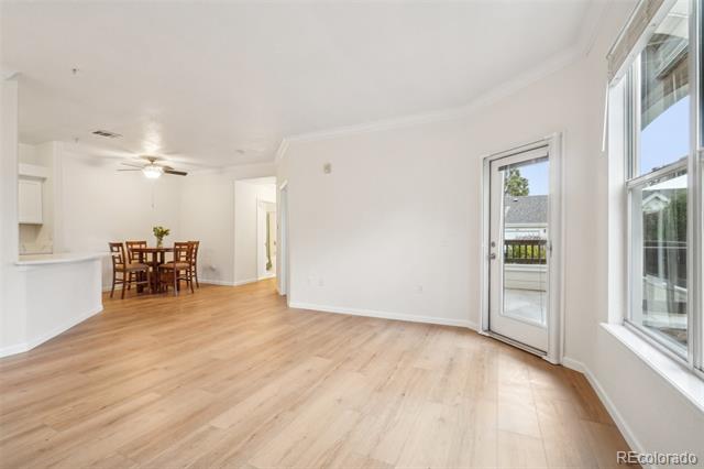 Open living and dining area with light wood floors, a dining set, and a glass balcony door.