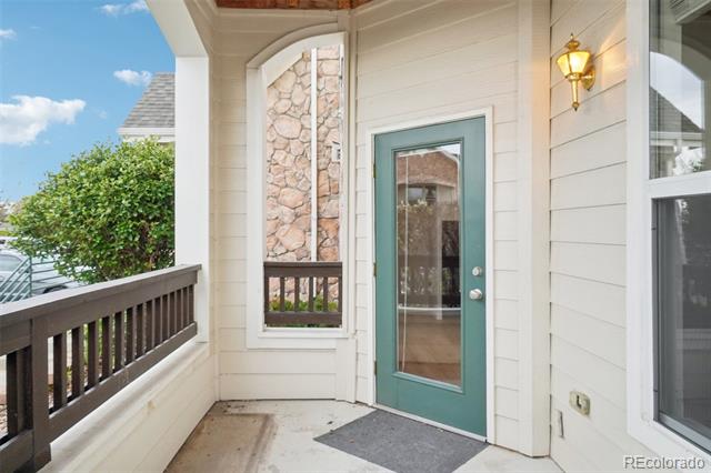 Condo entry porch with teal-framed glass door, stone accent wall, and dark railing.