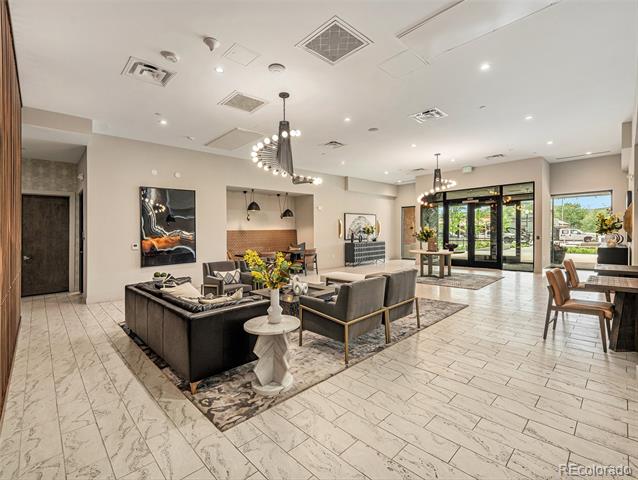 Furnished building lounge with a seating area, dining tables, and glass entry doors.