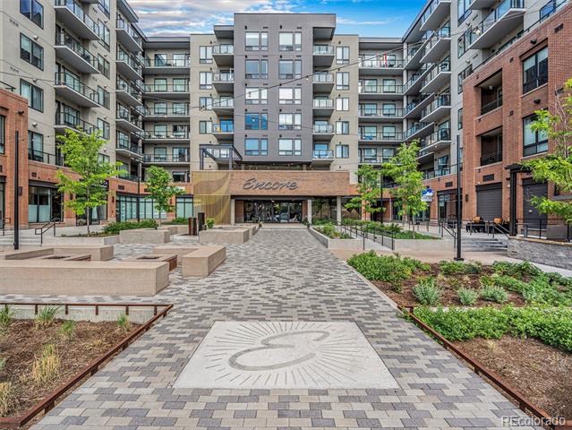 Encore condominium building surrounding a landscaped courtyard with patterned paving and raised planters.