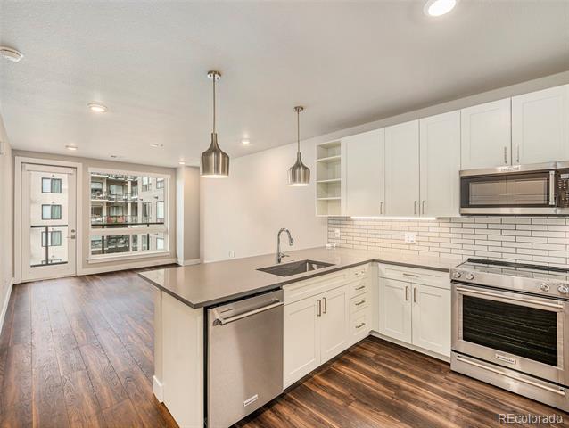 Condominium kitchen with white cabinetry, stainless steel appliances, and a large island beside glass doors.