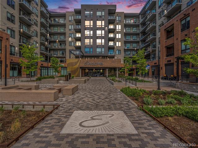 Condominium courtyard at dusk with brick paving, landscaped planters, and surrounding apartment buildings.