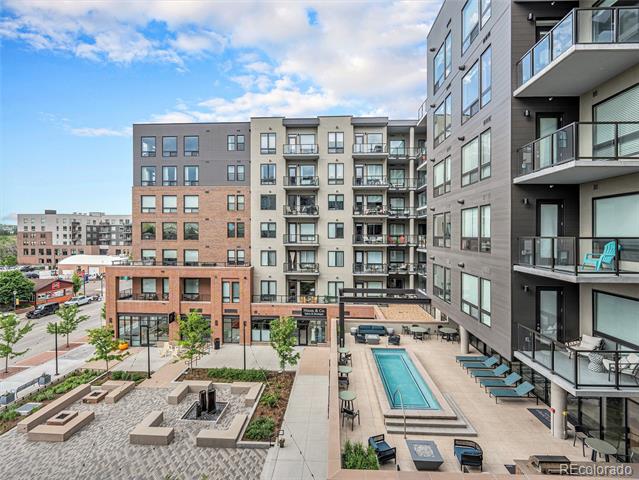 Apartment building courtyard with a narrow swimming pool, patio seating, and balconies.
