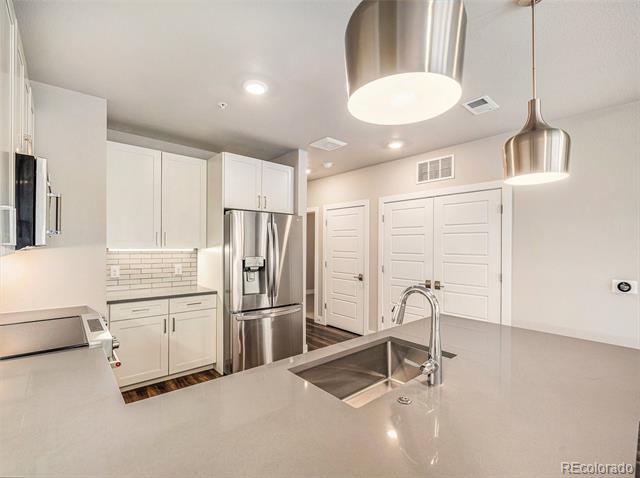 Modern kitchen with a large gray island, stainless steel appliances, and white shaker cabinets.