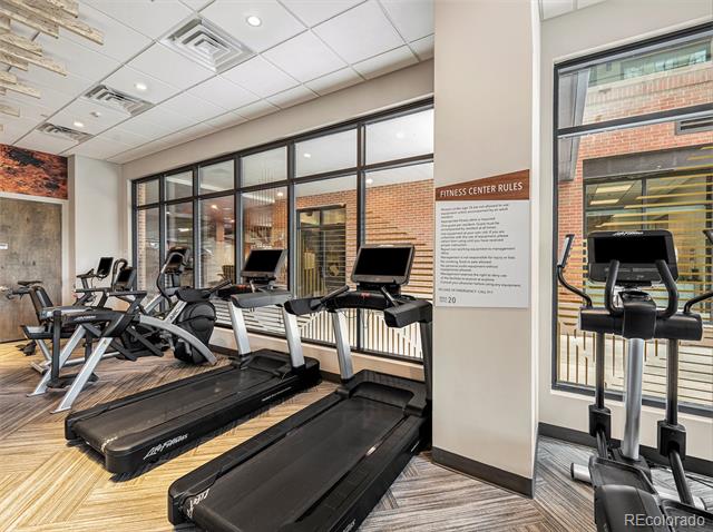 Condominium fitness center with treadmills and elliptical machines beside large windows.