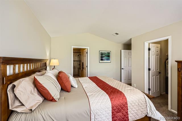 Bedroom with a dark wood headboard and white quilt with a red runner.