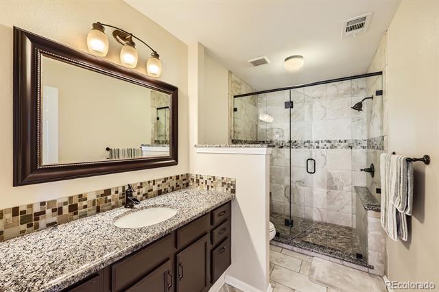 Bathroom with a dark wood vanity and a glass-enclosed marble-look tile shower.
