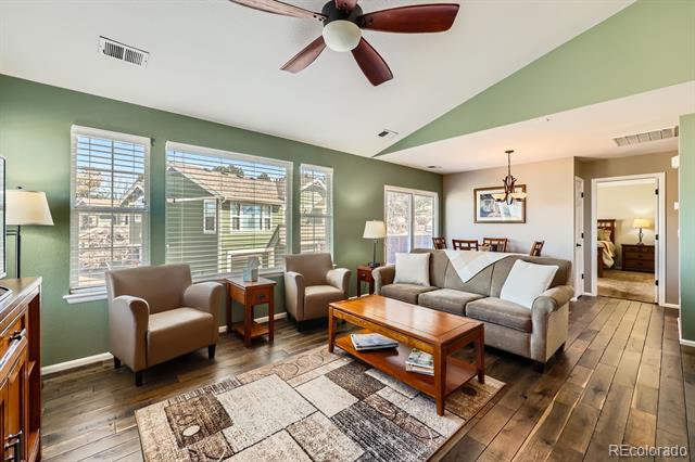 Living room with sage-green walls, tall windows, wood floors, and a sectional sofa.