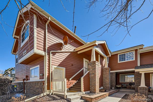 Two-story red-sided attached home with brick accents, an upper balcony, and a covered entrance.