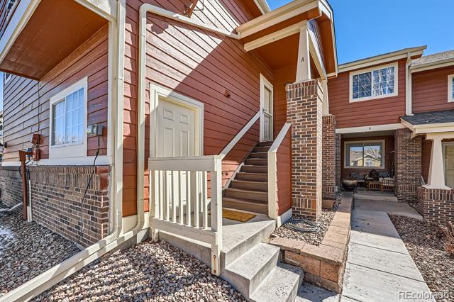 Red-sided home entry with white porch railings, brick columns, and a walkway to the front steps.