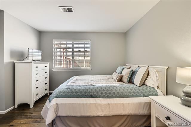 Bedroom with a white bed, blue-gray bedding, window blinds, and a white dresser.