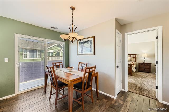 Dining area with a wooden table beside a patio door and an open view into a bedroom.