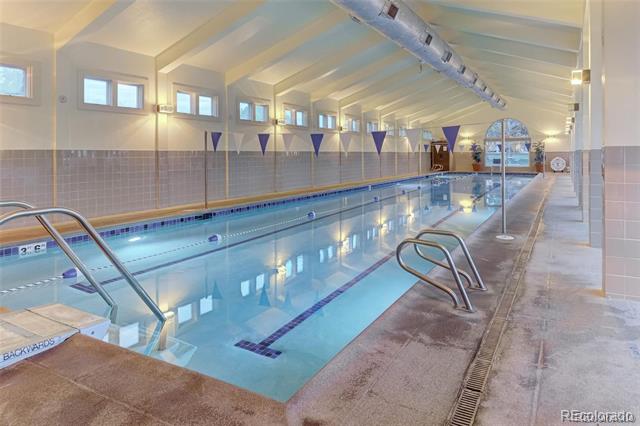 Indoor lap pool with blue water, lane markers, and a high vaulted ceiling.