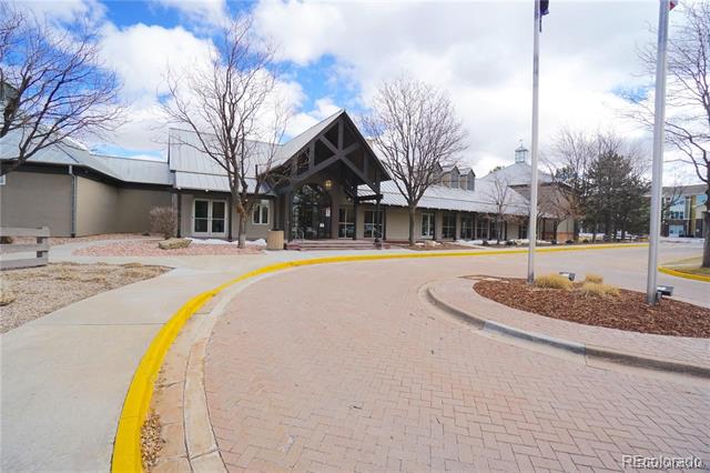 Building entrance with timber trusses, glass doors, and a curved brick driveway edged in yellow.