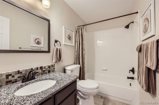 Bathroom with a granite vanity and oval sink beside a tub and shower.