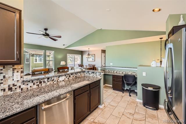 Kitchen with granite counters, mosaic backsplash, stainless steel appliances, and a small desk nook.