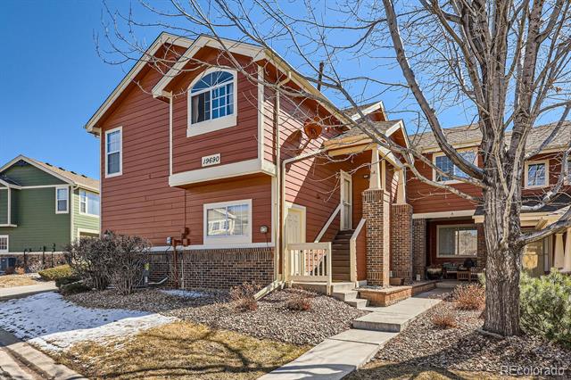 Two-story red-sided home with brick base, covered entry, and attached garage.