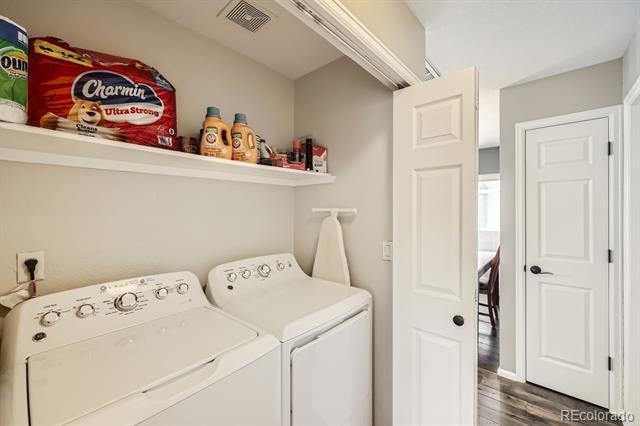 Laundry room with side-by-side washer and dryer beneath a shelf of supplies.