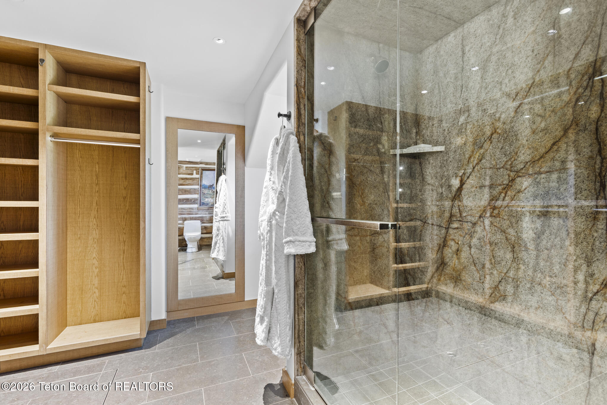 Bathroom with a stone walk-in shower, built-in bench, and open wood storage shelves.