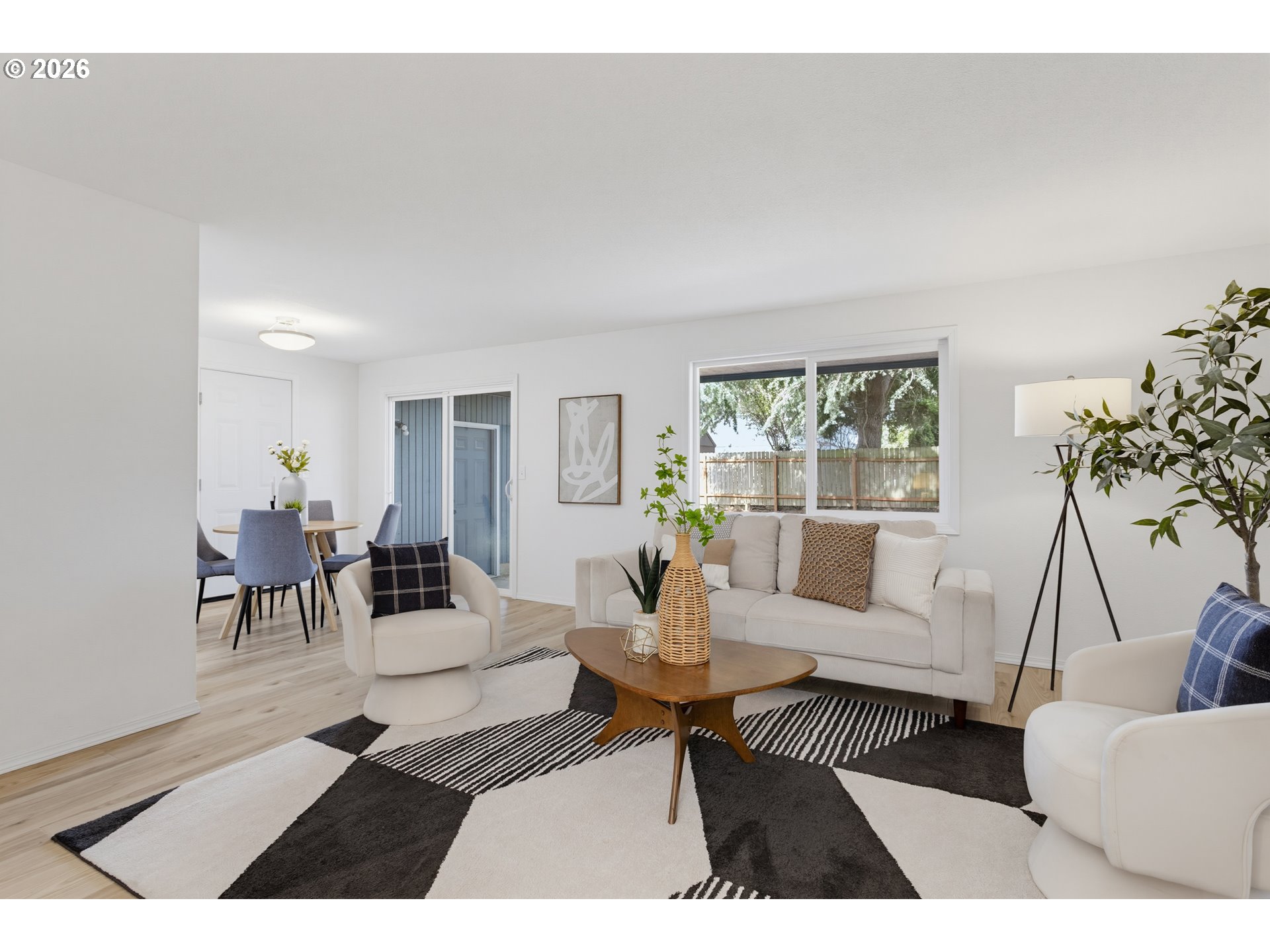 Staged living room with cream sofa, patterned rug, and adjoining dining area.