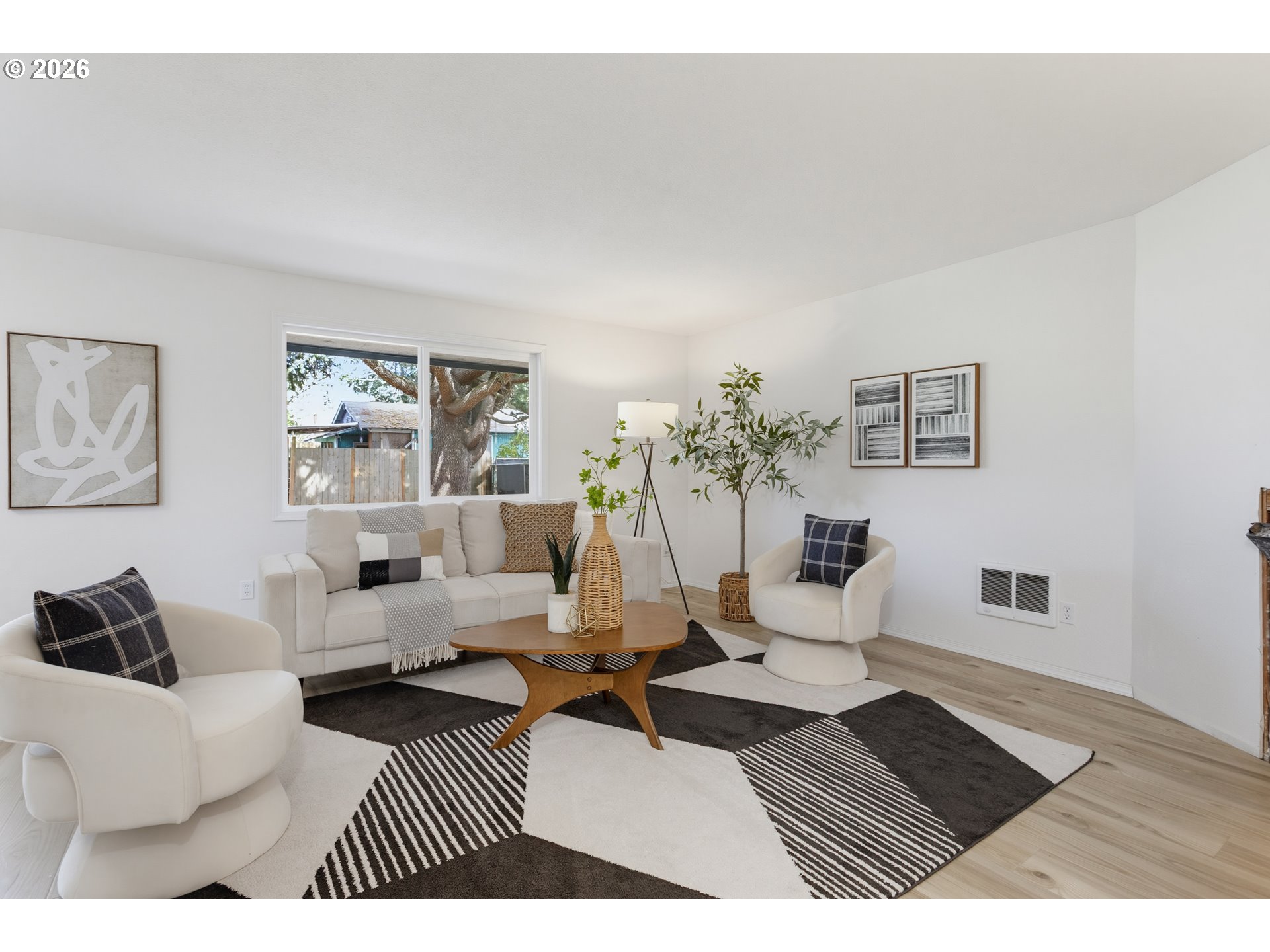 Living room with white seating, a wooden coffee table, and a black-and-white geometric rug.