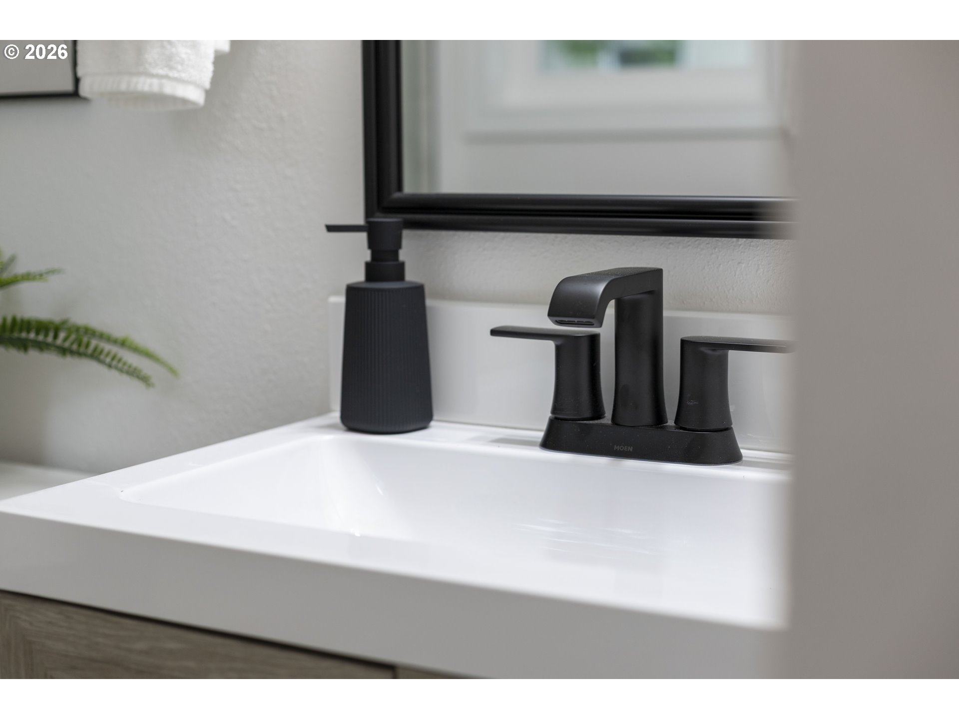 Bathroom vanity with a white sink, matte black faucet, and matching soap dispenser.