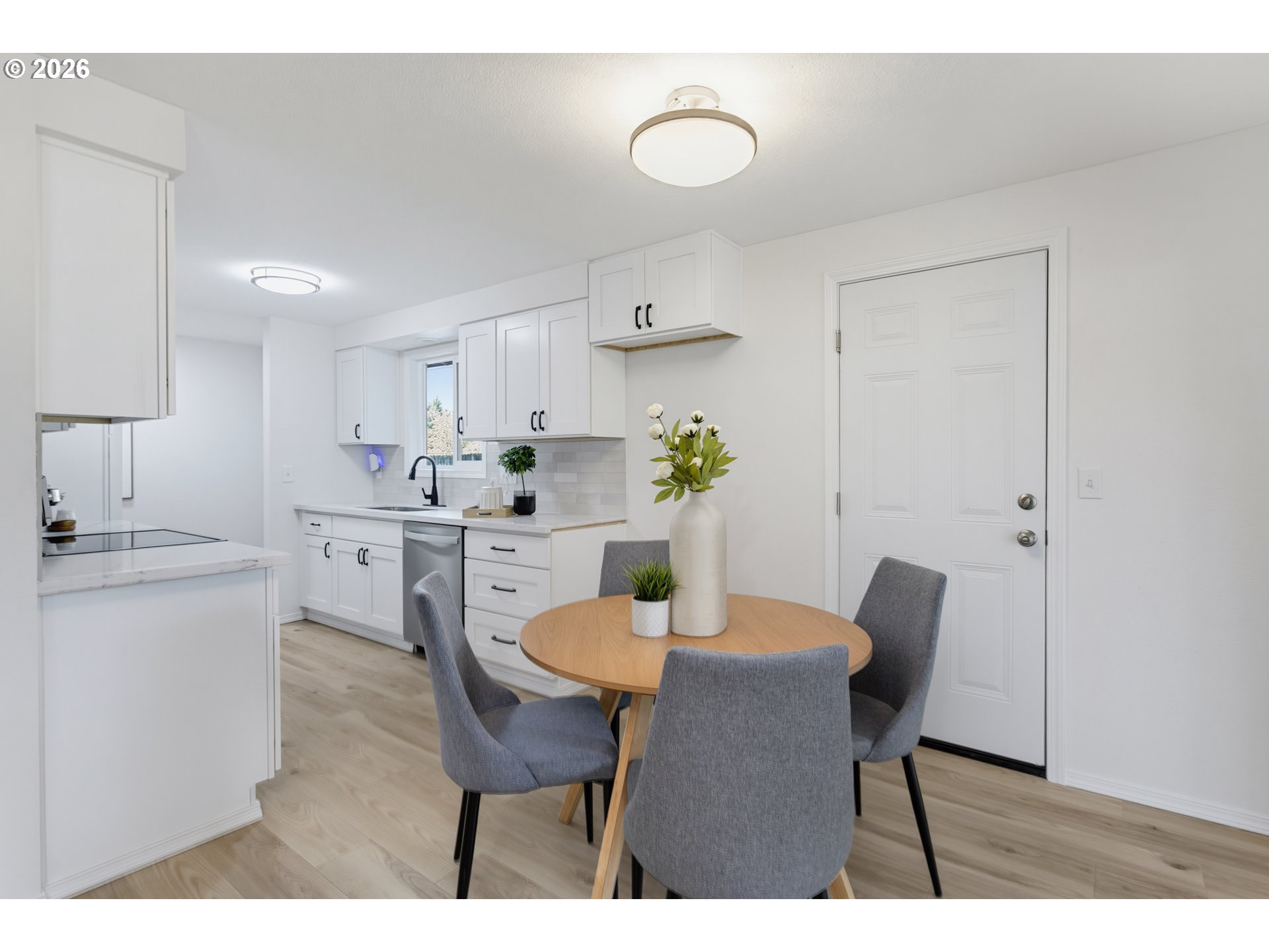 Kitchen and dining area with white cabinetry, a round wood table, and gray chairs.