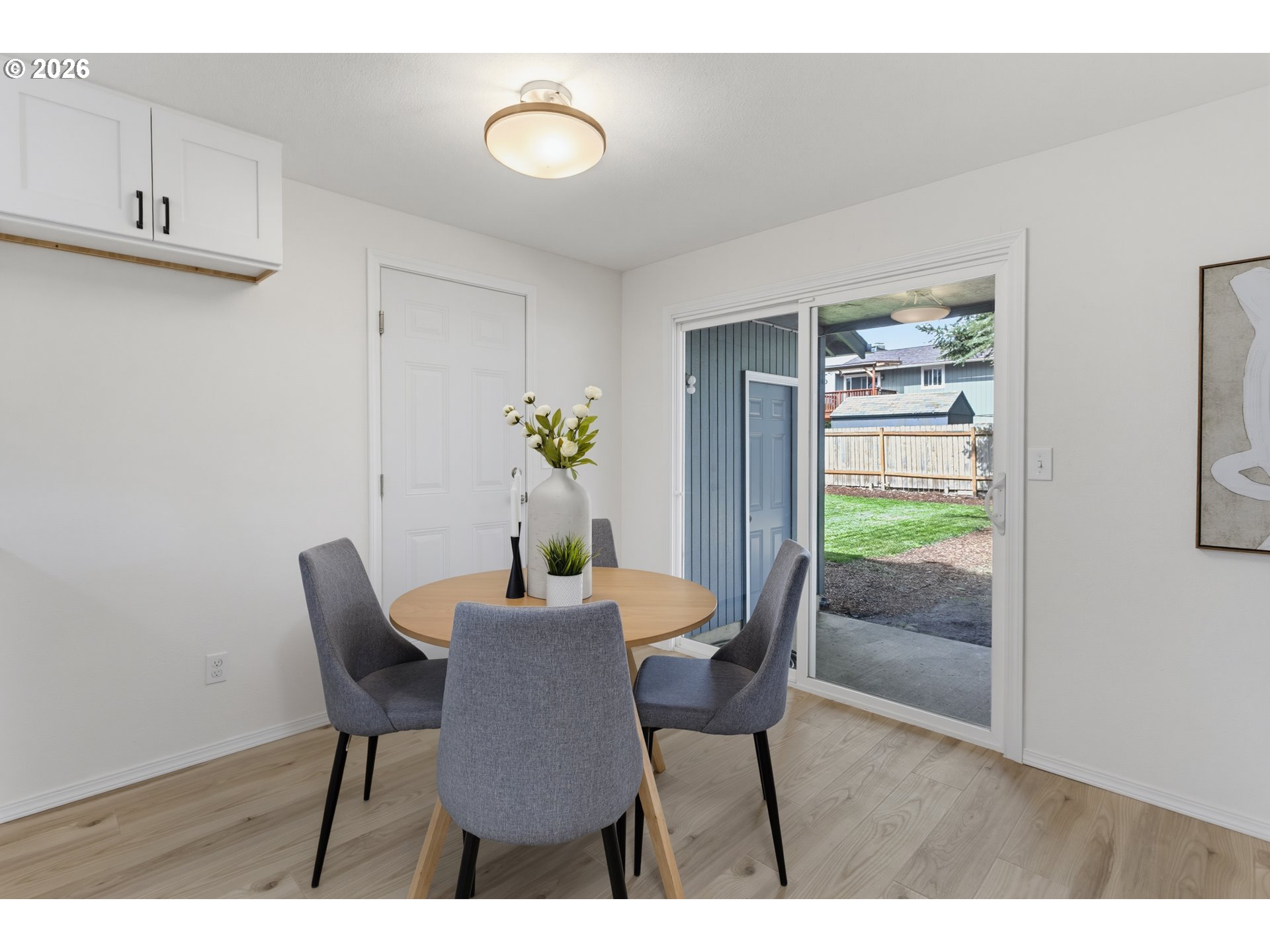 Dining area with a round wood table and sliding glass door opening to a fenced yard.