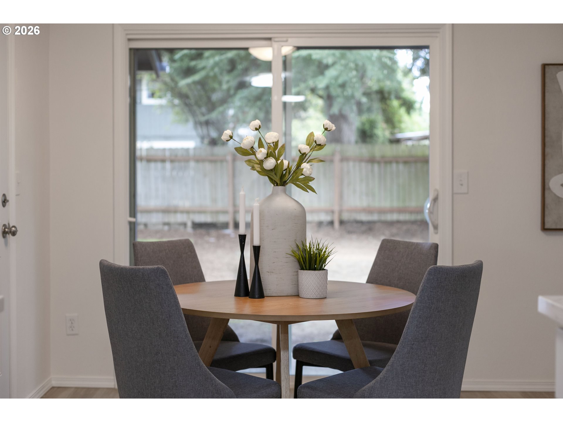 Dining room with a round wood table and gray chairs beside a sliding glass door.