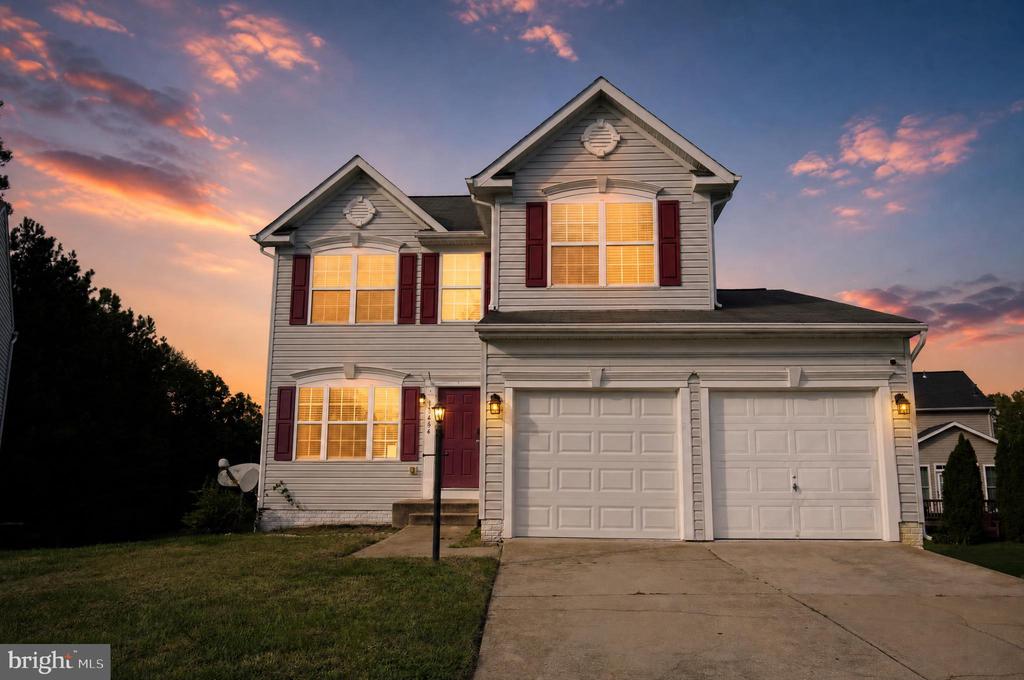 Two-story gray house with red shutters and a double garage at dusk.