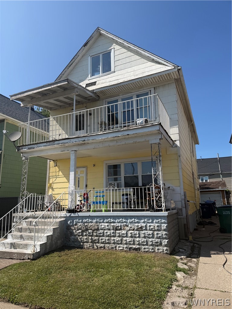 Two-story house with a covered porch, upper balcony, and stone foundation.
